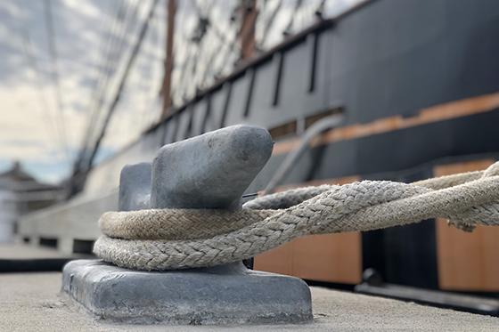 a closeup of a clete wrapped with a rope securing a large vessel to a dock