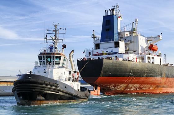 A smaller tug in front of a larger vessel