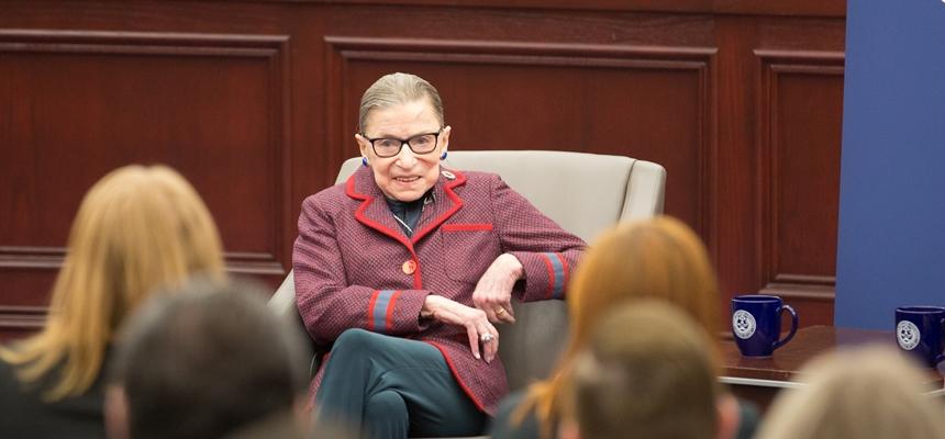Ruth Bader Ginsburg sits in an armchair in front of a room of RWU students.