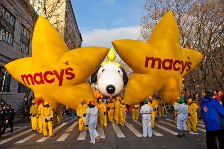 Macy's Thanksgiving Parade balloon handlers with Snoopy Balloon and 2 Star Shaped Balloon with "Macy's" logo