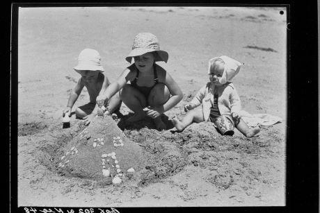 3 children building a sand castle on a beach