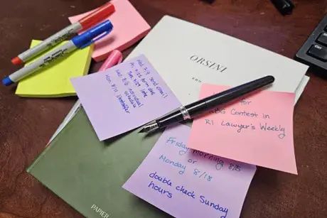 Stacks of papers, sticky note pads, and pens on a flat surface