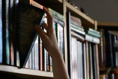 Hand removing a book from a bookshelf