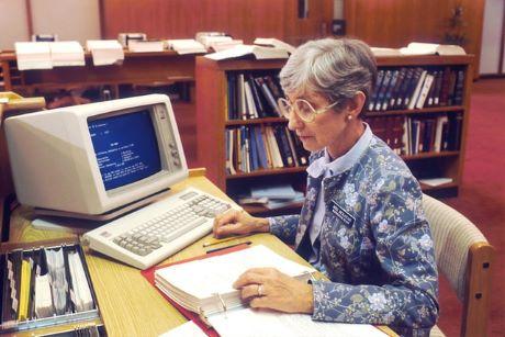 Woman at desk with computer and books.