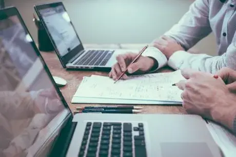 Two laptop computers and papers with writing.