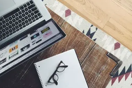 Laptop computer, open notebook, and a pair of eye glasses