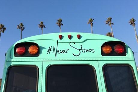 School bus in front of palm trees with #Never Stress written on back door