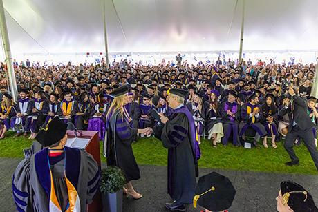A graduate receives their degree on stage at commencement