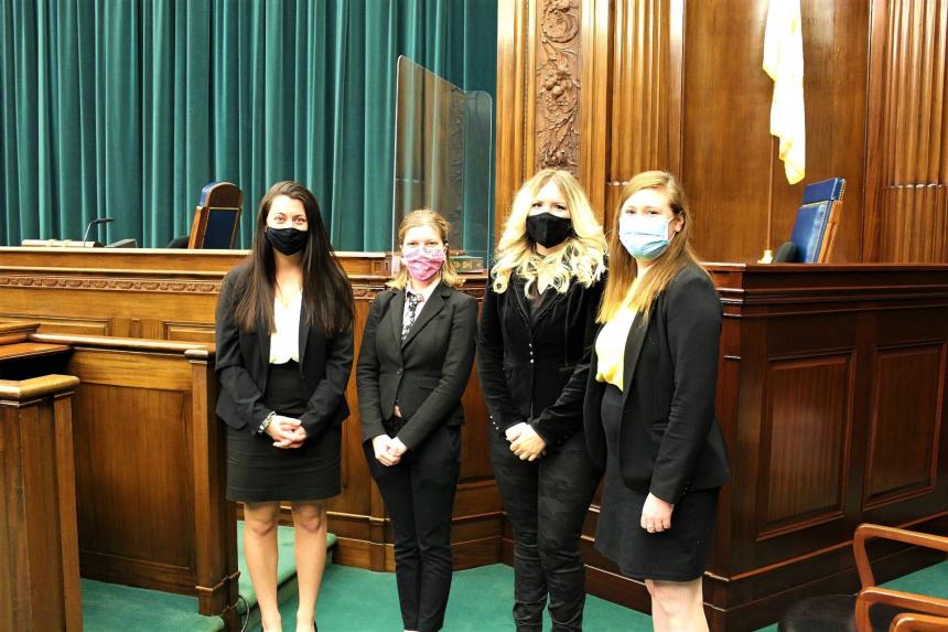 A group of four people pose wearing masks